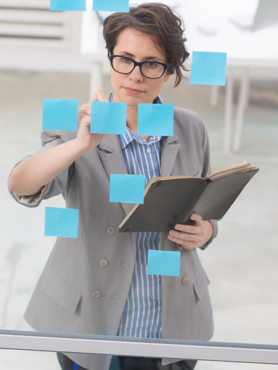 Working organizing sticky notes on a glass board